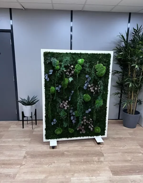 Une cloison végétale mobile devant un mur de bureau avec une plante de chaque côté.